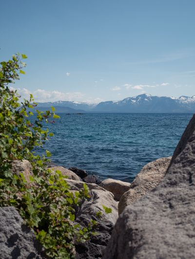 Lake Tahoe visible between 2 rocks with beautiful mountains in the background.